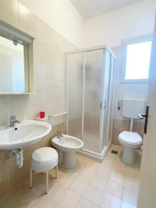 een badkamer met een douche, een toilet en een wastafel bij Villa Giulia in Bibione
