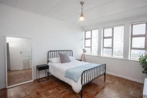 a bedroom with a bed in a room with windows at Cremorne on Beach Road in Summerstrand