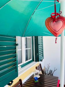 a green umbrella and a bench with a heart hanging from it at Almograve Beach House in Almograve