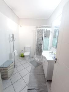 a white bathroom with a toilet and a sink at Galini apartment near sea, port and airport in Artemida