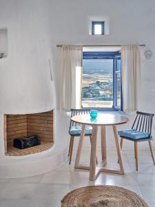 a table and two chairs in a room with a fireplace at Leticia Villa with pool with amazing sea views, Paros in Márpissa