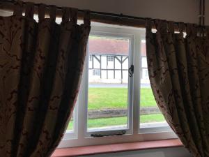 un par de cortinas delante de una ventana en Village period cottage, en Wolston