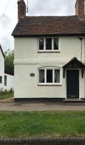 a white house with two windows and a door at Village period cottage in Wolston