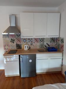 a kitchen with white cabinets and a stainless steel refrigerator at Roko Apartments in Selce
