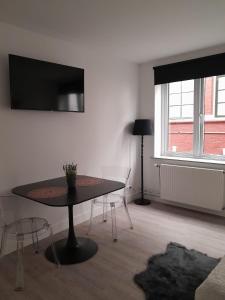 een woonkamer met een tafel en een tv aan de muur bij Annalisa Guest House Centrum in Enschede