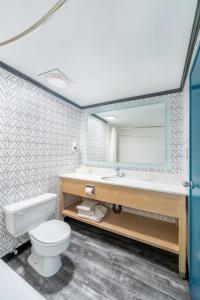 a bathroom with a toilet and a sink and a mirror at Sternwheeler Hotel & Conference Centre, Trademark by Wyndham in Whitehorse