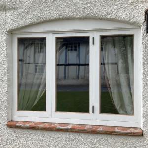 a window with white curtains in a building at Village period cottage in Wolston