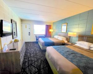 a hotel room with two beds and a flat screen tv at Beach Carousel Virginia Beach in Virginia Beach