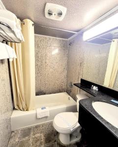 a bathroom with a toilet and a tub and a sink at Beach Carousel Virginia Beach in Virginia Beach