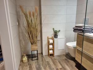 a bathroom with a toilet and some plants on the floor at Apple Apartments - Gdańska PRYWATNE MIEJSCE PARKINGOWE in Łódź