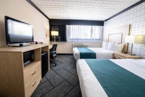 a hotel room with two beds and a flat screen tv at Sternwheeler Hotel & Conference Centre, Trademark by Wyndham in Whitehorse