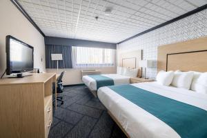 a hotel room with two beds and a flat screen tv at Sternwheeler Hotel & Conference Centre, Trademark by Wyndham in Whitehorse