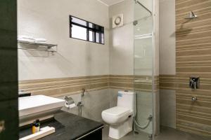a bathroom with a toilet and a sink and a shower at Aloha Holiday Resort in Baga