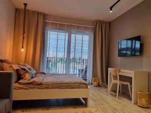 a bedroom with a bed and a desk and a window at Apple Apartments - Gdańska PRYWATNE MIEJSCE PARKINGOWE in Łódź