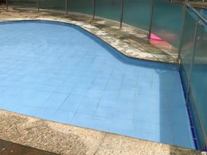 an empty swimming pool with blue tiles on the ground at Águas da Serra Apart Service - acesso ao rio e vista pra serra in Rio Quente