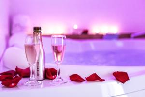 dos copas de champán y rosas rojas en una mesa en Pasithèa Suite, en Ceglie Messapica