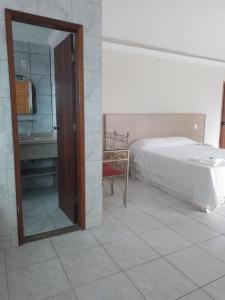 um quarto com uma cama, um espelho e uma cadeira em Hotel Recanto da Itália em Nova Friburgo