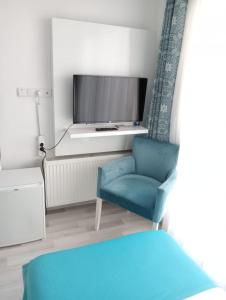 a living room with a tv and two blue chairs at Daffne Otel in Canakkale