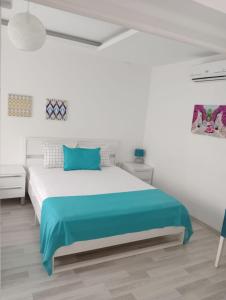 a white bedroom with a large bed with blue sheets at Daffne Otel in Canakkale
