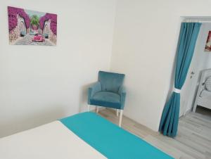 a bedroom with a bed and a blue chair at Daffne Otel in Canakkale