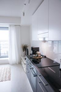 a white kitchen with a black counter top at Huoneisto Tampereen paraatipaikalla. 14. kerros. in Tampere