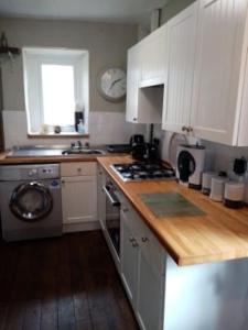 a kitchen with white cabinets and a stove top oven at Bridge View Victorian Townhouse Central Aberystwyth Sleeps 6 in Aberystwyth