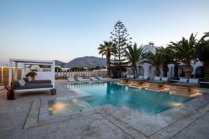 una piscina con tumbonas y palmeras en Louis Studios Santorini, en Kamari