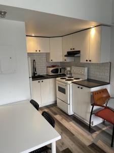 a kitchen with white cabinets and a table and chairs at Faubourg Ste Cath in Montreal