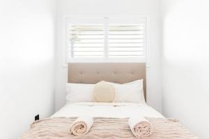 a white bedroom with a bed with two pink slippers on it at Stunning Views at Alex Heads, 2 BR Stylish Apt in Alexandra Headland