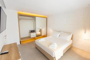 a bedroom with a white bed and a brick wall at The Angeliki Boutique Hotel in Skala Rachoniou