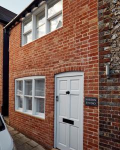 um edifício de tijolos com uma porta branca e duas janelas em Norton Studio em Arundel