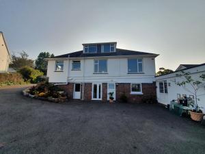 a large white house with a large driveway at Lovely private studio room with own kitchen and bathroom. Set in the popular area of Shiphay in Torquay and only a short walk from Torbay Hospital in Torquay