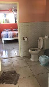 a bathroom with a toilet and a bedroom with a bed at Magical Garden in Savaneta