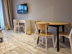 Cette chambre dispose d'une table, de chaises et d'un bureau. dans l'établissement Apple Apartments - Gdańska PRYWATNE MIEJSCE PARKINGOWE, à Łódź