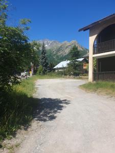 un chemin de terre à côté d'un bâtiment avec des montagnes en arrière-plan dans l'établissement Magnifique studio, centre, parking privée,terrasse, au Monêtier-les-Bains