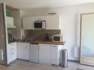 a kitchen with white cabinets and a microwave at Magnifique studio, centre, parking privée,terrasse in Le Monêtier-les-Bains