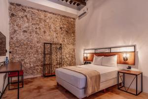 1 dormitorio con cama y pared de ladrillo en Hotel HO Merida en Mérida