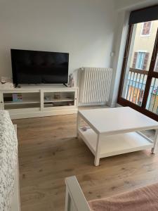 sala de estar con TV y mesa de centro blanca en La Madeleine, en Annecy