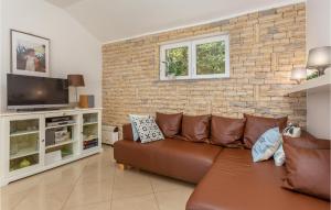 a living room with a brown couch and a brick wall at Awesome Home In Njivice With 3 Bedrooms, Wifi And Outdoor Swimming Pool in Njivice