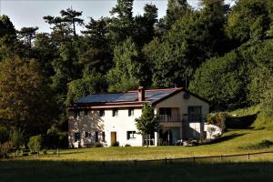 una casa blanca con techo solar en un campo en GUESTHOUSE Idila pod Nanosom, en Senožeče
