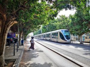 a woman walking on the sidewalk next to a train at Appartement idéal pour découvrir la ville in Rabat