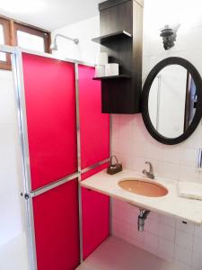 La salle de bains est pourvue de portes coulissantes rouges et d'un lavabo. dans l'établissement Pousada Recanto do Turvo, à Capitólio
