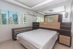 um quarto com uma cama grande e uma janela grande em Apartamento c/ hidromassagem 3 Suítes em Meia Praia em Itapema