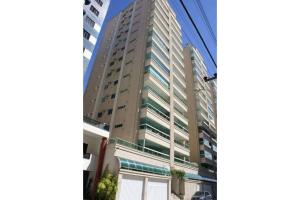 a tall building with glass windows in a city at Apartamento Almeida e Moraes 3 Suítes com Hidro in Itapema