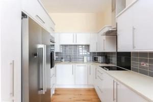 a kitchen with white cabinets and a stainless steel refrigerator at Stylish 2 Bedroom Apartment in Greenwich in London