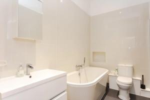 a white bathroom with a tub and a toilet and a sink at Stylish 2 Bedroom Apartment in Greenwich in London