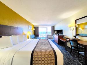 バージニアビーチにあるOcean Resortの大きなベッドとデスクが備わるホテルルームです。