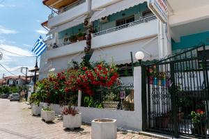 a building with red flowers in front of a fence at ΤΗΕRAMVOS in Pefkochori +37 photos