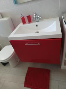 ein Bad mit einem roten und weißen Waschbecken und einem WC in der Unterkunft Nikità in Venaria Reale