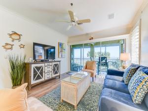 a living room with a blue couch and a ceiling fan at South Beach Club 205, 3 Bedrooms, Sleeps 6, Ocean View, 2nd Floor, Elevator in Flagler Beach